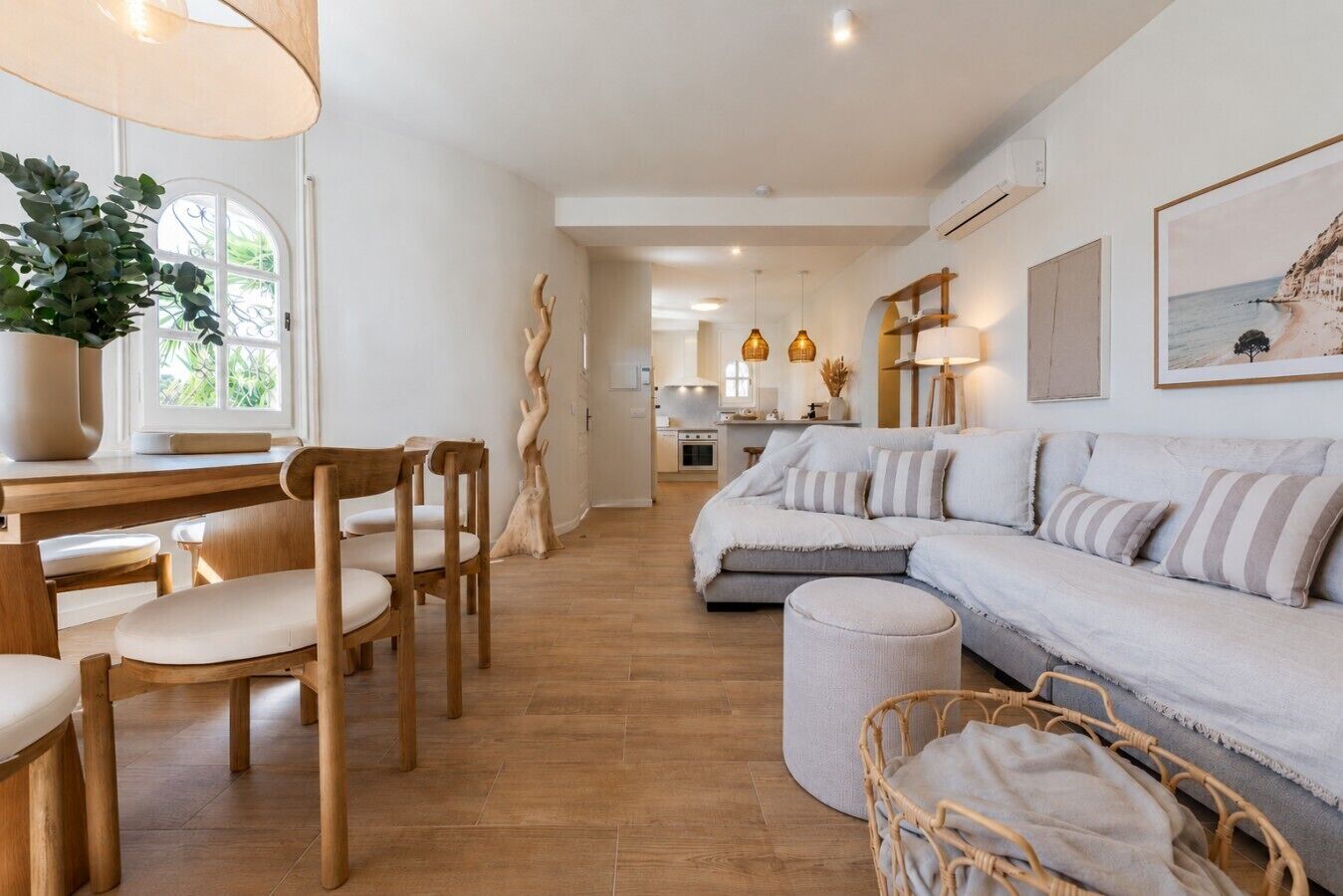 Un salon moderne avec un canapé, des fauteuils, une table à manger et une cuisine en arrière-plan.