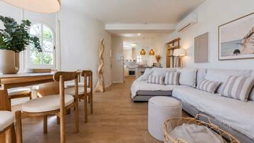 Un salon moderne avec un canapé, des fauteuils, une table à manger et une cuisine en arrière-plan.