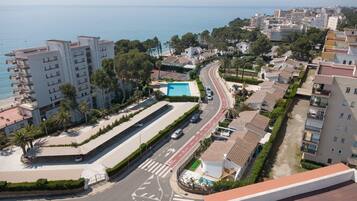 Un quartier résidentiel situé sur la côte, avec une route sinueuse, une piscine et des immeubles dotés de balcons.
