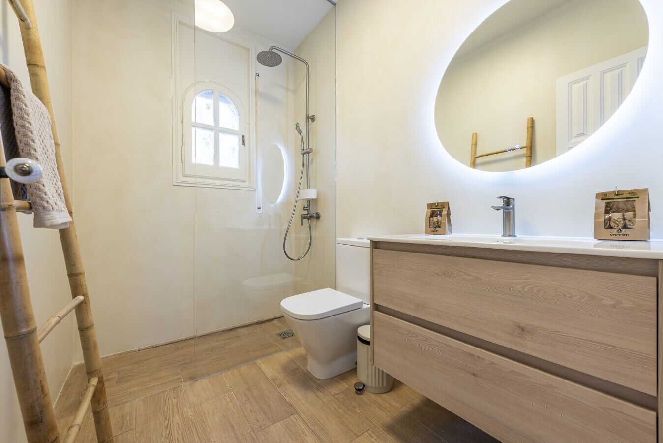 Een badkamer met toilet, douche, wastafel met spiegel en een handdoekhouder.