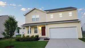 A two-story residential house with a front porch, a garage, and a well-maintained lawn.