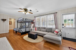 Une pièce comprenant un lit superposé, un canapé, une table basse et un ventilateur de plafond.