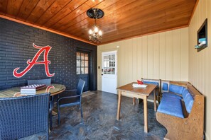 Ein Zimmer mit Holzboden, einem Kronleuchter, einem Tisch mit Stühlen, einer Couch und einer Wand mit einem großen Buchstaben 'A'.