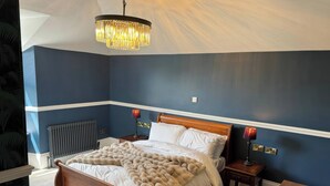 Ein Schlafzimmer mit einem hölzernen Bett, einer Kristallleuchtre, Nachttischlampen und einer Heizung.