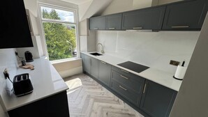 Eine moderne Küche mit Fischgratparkett, einem Fenster mit Blick ins Grüne und einem eingebauten Herd.