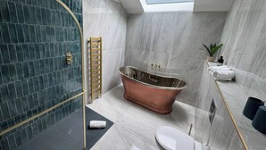 Ein modernes Badezimmer mit einer freistehenden Badewanne, einer Duschkabine aus Glas und einem Oberlicht.