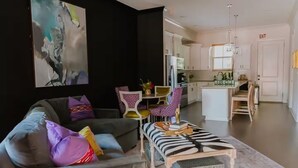 Un salon moderne comprenant un canapé, une table basse et un coin repas avec des chaises.