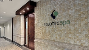 Ein Flur mit einer gefliesten Wand, einer Tür und dem Logo von 'sapphire spa'.