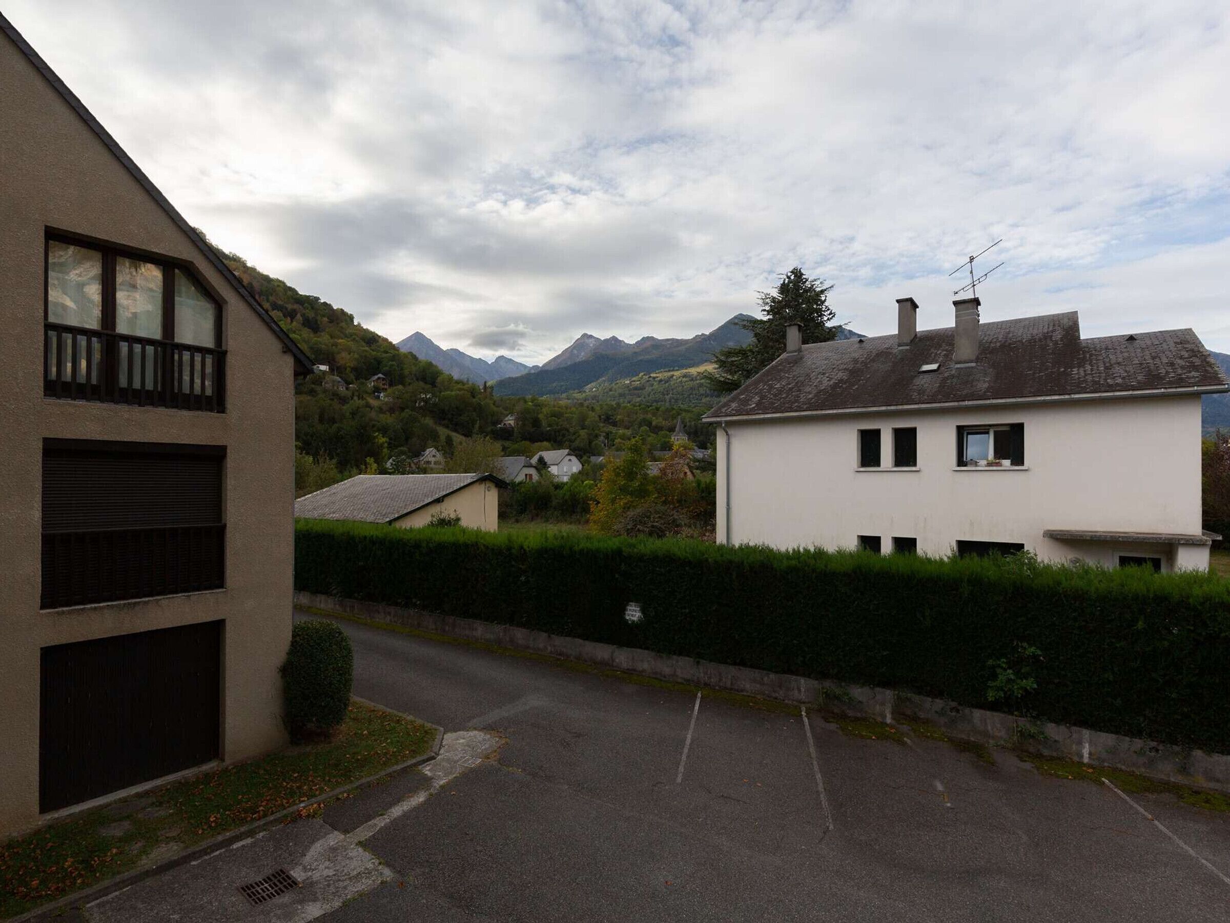 A residential street with houses, a garage, and a mountain backdrop.