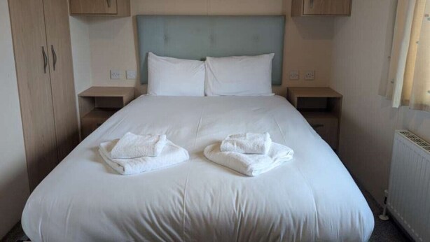 A hotel room with a large bed, wooden cabinets, and a radiator.