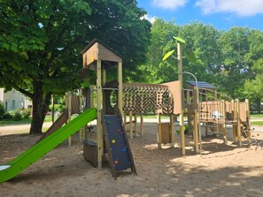 Ein Spielplatz mit Rutsche, Klettergerüsten und einem Holzspielhaus.
