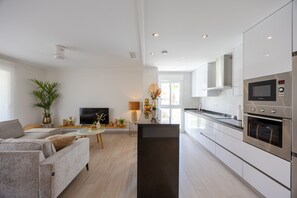 A modern kitchen with built-in appliances, a dining area with a table and chairs, and a living room with a sofa and television. - Casa BiBo – Comfort & Relax on the Costa Blanca (Orihuela Costa)
