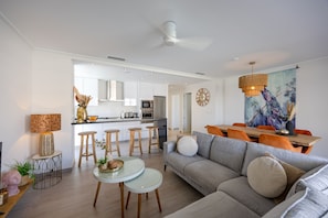 A modern living room with a grey sofa, round coffee table, and a dining area with orange chairs. - Casa BiBo – Comfort & Relax on the Costa Blanca (Orihuela Costa)