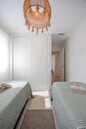 A room with two beds, a woven hanging light fixture, and a view into another room. - Casa BiBo – Comfort & Relax on the Costa Blanca (Orihuela Costa)
