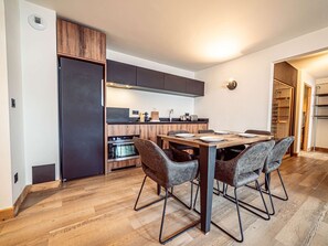 Eine moderne Küche mit Essbereich, Holzschränken und einem eingebauten Backofen.