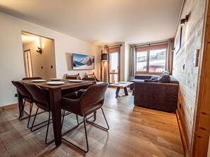Ein modernes Interieur mit Essbereich, Sofa und großen Fenstern.