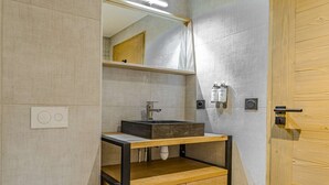 Een badkamer met een houten wastafel, een spiegel, een wasbak en een douchegordijn.