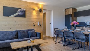 Een moderne woonkamer met een bank, salontafel en een eethoek met stoelen.