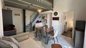 Et moderne interiør med trappe, spiseplads og en opholdsstue med sofa og stole.