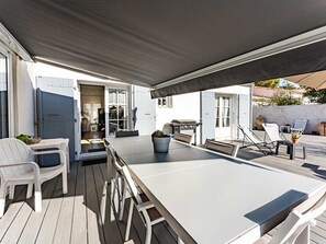 Una terrazza esterna con un tavolo lungo, sedie e una zona coperta.