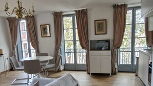 Una habitación con cama, una mesa de comedor con sillas, un microondas y un televisor.
