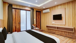 Ein Hotelzimmer mit einem Bett, einem an der Wand befestigten Fernseher, einem Sessel und einer Schiebetür.
