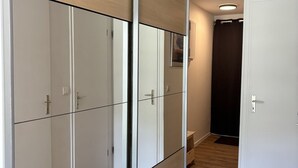 Ein Flur mit einem raumhohen Spiegelkleiderschrank, einer Tür mit Griff und einer kleinen Bank.