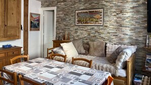 A cozy room with a stone wall, a wooden sofa, a dining table, and a poster on the wall. - Bright, peaceful apartment - 8 guests (Cauterets)