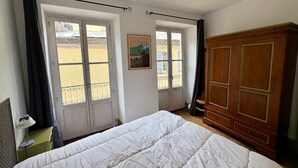 A bedroom with a bed, two windows, a wardrobe, and a painting on the wall. - Bright, peaceful apartment - 8 guests (Cauterets)