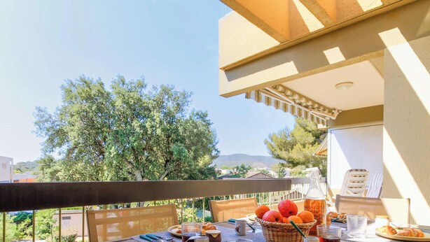Ein Balkon mit einem Frühstückstisch, gedeckt mit Obst, Brot und Getränken.