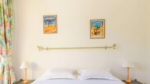 Ein Hotelzimmer mit einem Bett, zwei Wandlampen und zwei gerahmten Postern an der Wand.