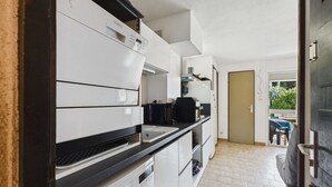Et kompakt køkken med vaskemaskine, kaffemaskine og komfur.