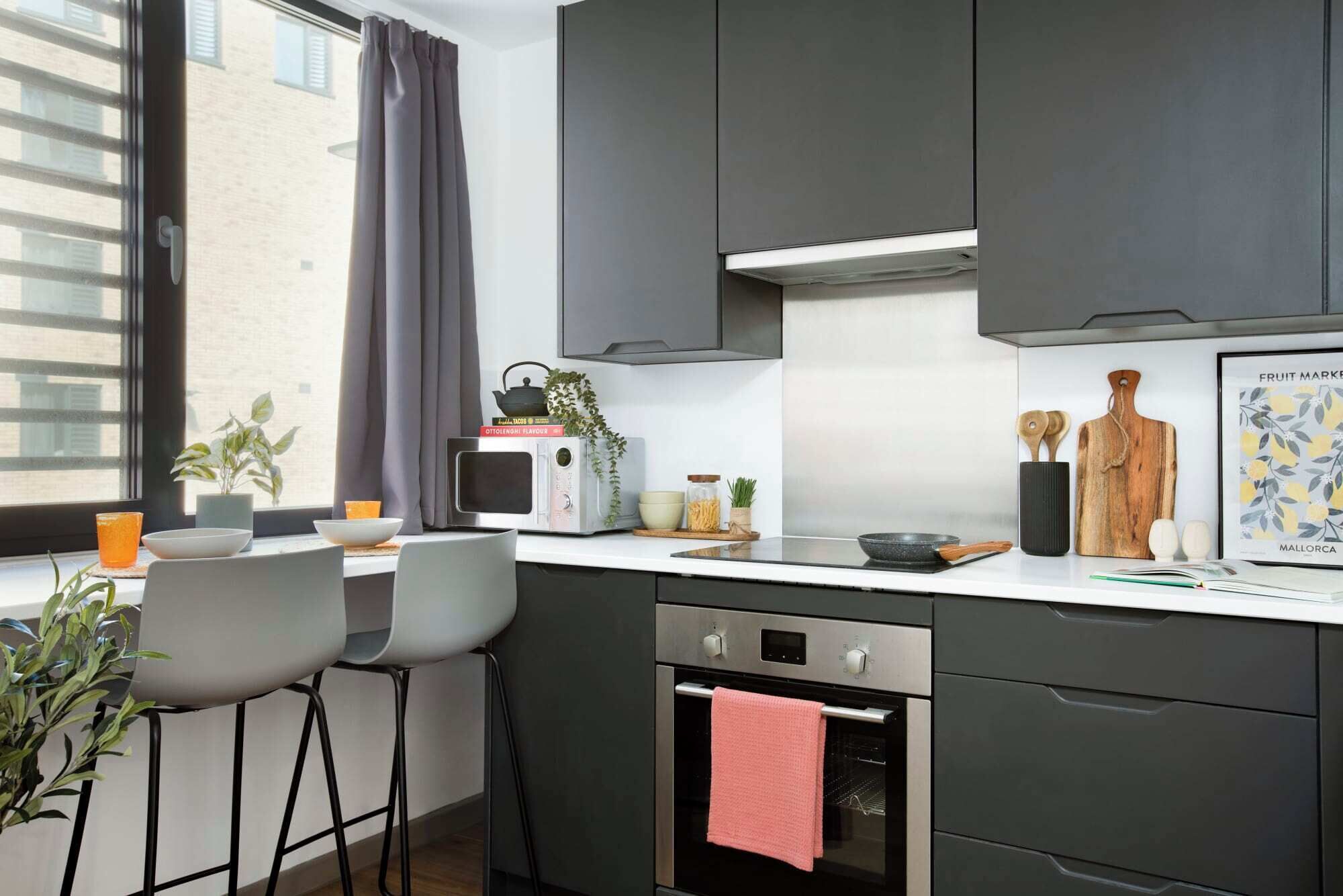 Une cuisine moderne équipée d’un four encastré, d’un four à micro-ondes et d’un coin repas avec des chaises et une table.