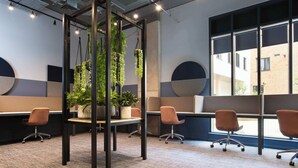 A modern office space with cubicles, ergonomic chairs, and potted plants.