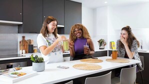 A modern kitchen with dark cabinets, a white countertop, and a dining table with placemats.