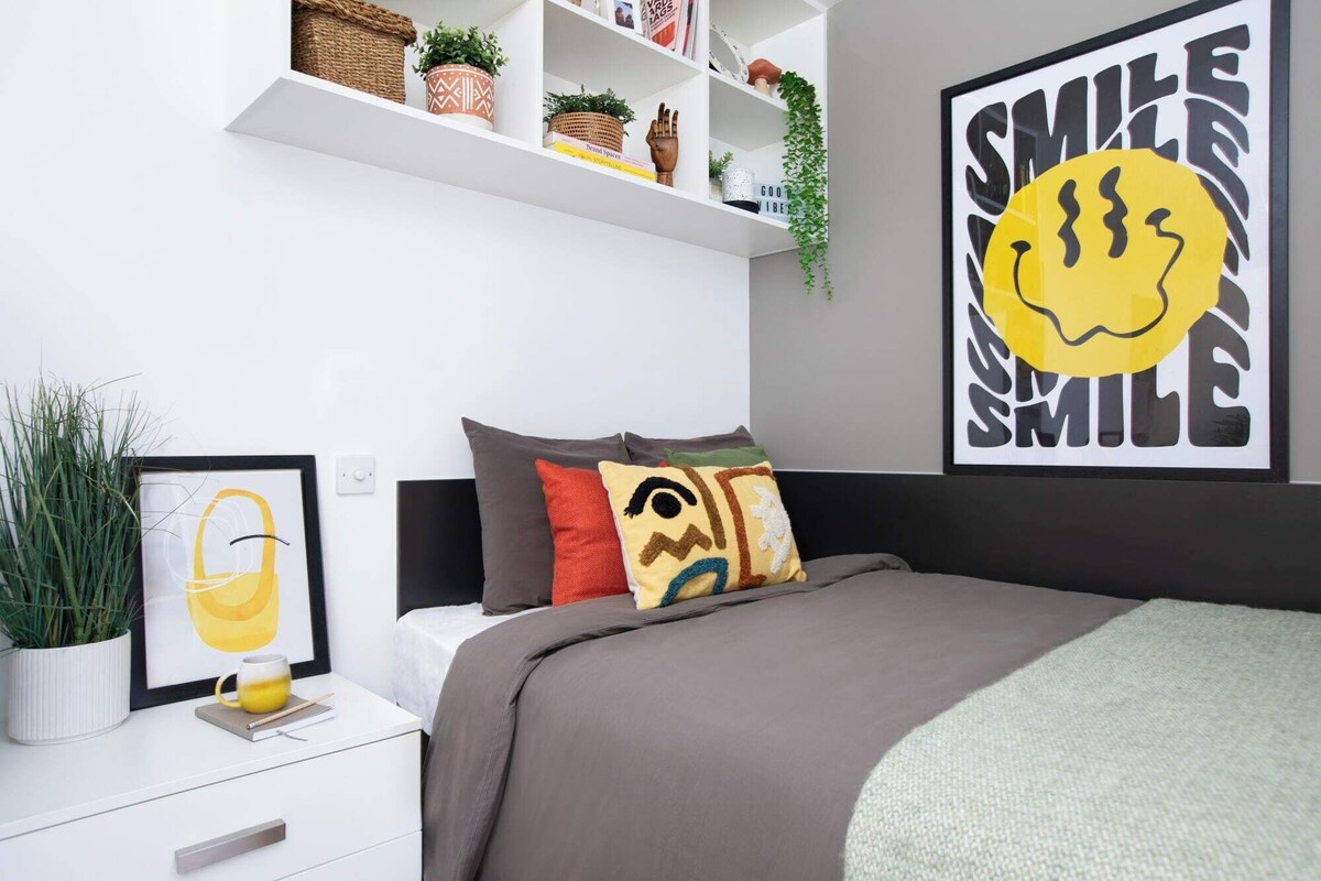A modern bedroom with a bed, bedside table, and a wall-mounted shelf with decorative items.
