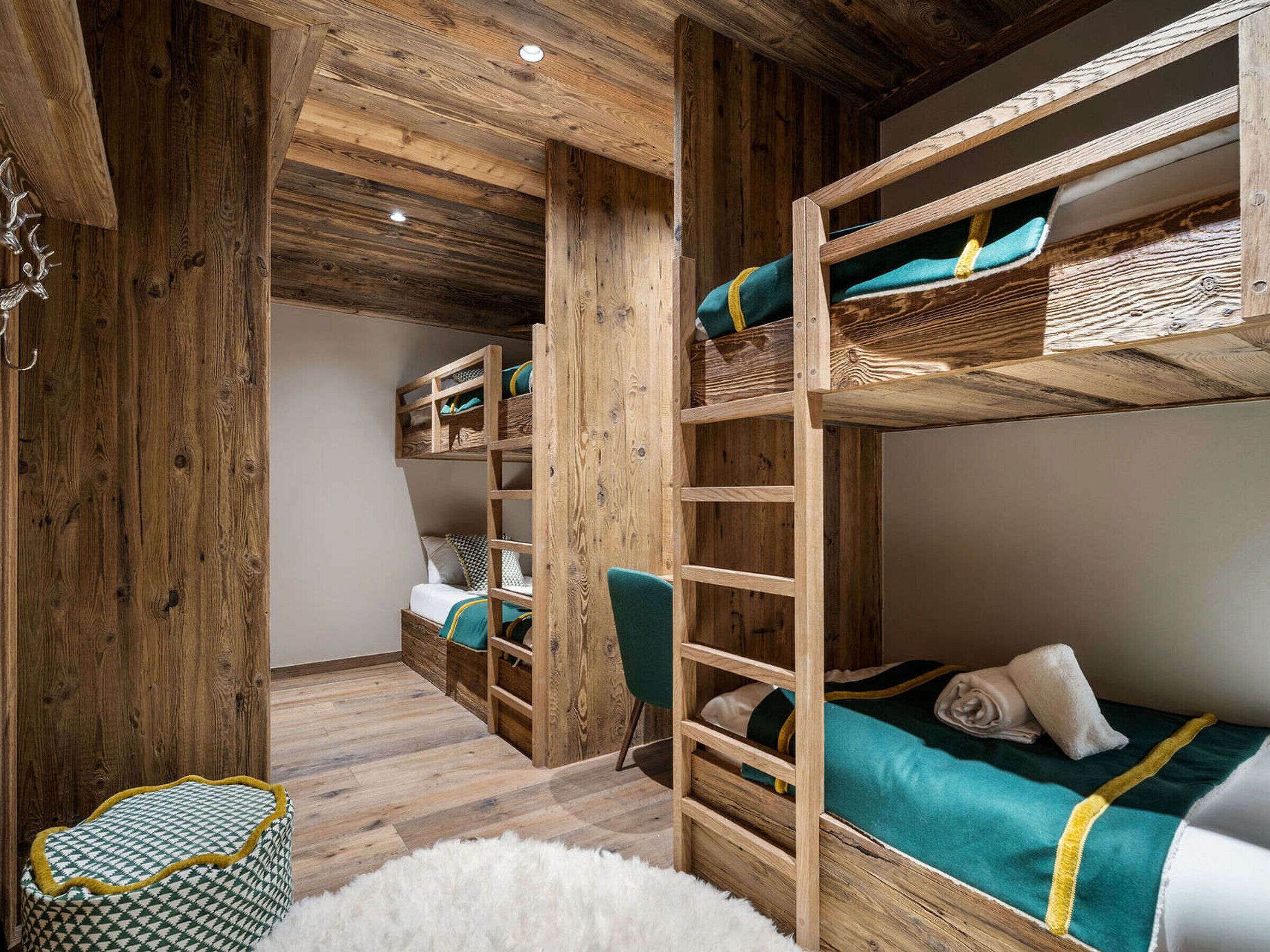 Une chambre avec un lit superposé, des murs et un plancher en bois, une échelle et une petite chaise.