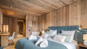 Puupaneloitu huone, jossa on sänky, yöpöydät, tuoli ja peili.
