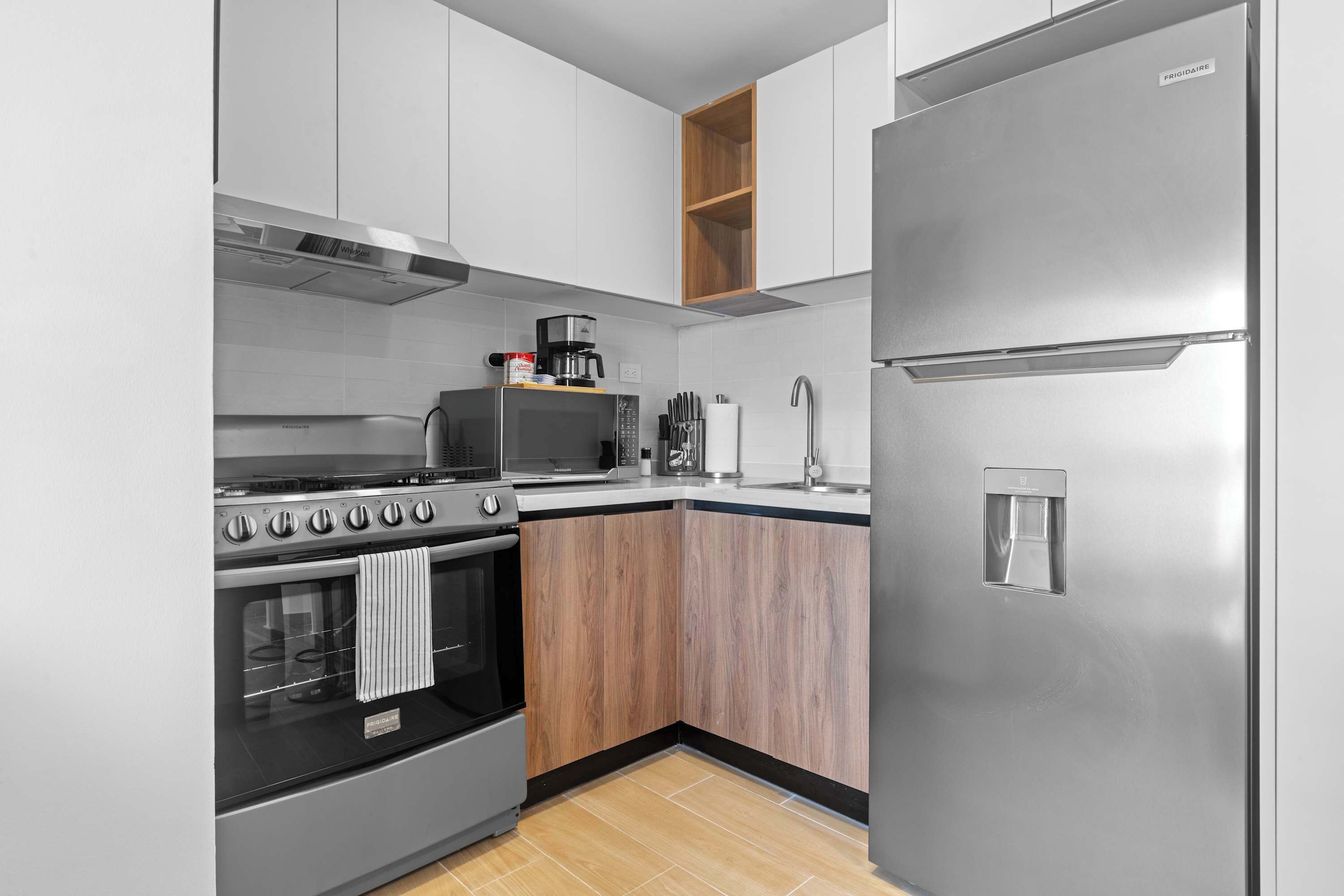 Une cuisine moderne dotée d’appareils électroménagers en acier inoxydable, de meubles en bois et d’un four à micro-ondes encastré.