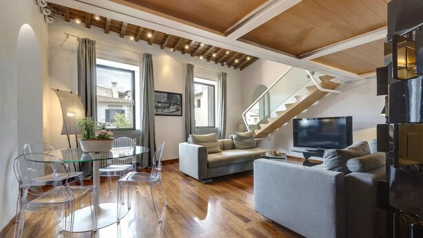 A modern living room with a sofa, TV, and dining area with clear chairs. - Elegant Duplex Apartment in the Heart of Florence - Walk to the Duomo (Firenze)