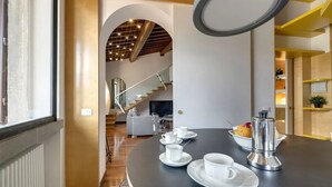 A modern kitchen with a round table set for tea, a coffee maker, and a staircase leading to another room. - Elegant Duplex Apartment in the Heart of Florence - Walk to the Duomo (Firenze)