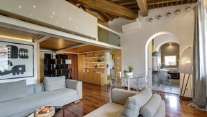 A modern living room with a sofa, a coffee table, and a dining area with a glass table and chairs. - Elegant Duplex Apartment in the Heart of Florence - Walk to the Duomo (Firenze)