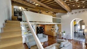 A spacious living area with a staircase, a sofa, and a kitchen area. - Elegant Duplex Apartment in the Heart of Florence - Walk to the Duomo (Firenze)