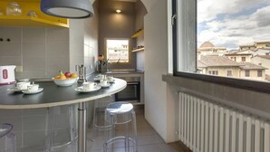 A modern kitchen with a round island, clear stools, and a view of buildings through a large window. - Elegant Duplex Apartment in the Heart of Florence - Walk to the Duomo (Firenze)