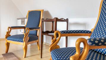 Una habitación con dos sillas de madera con tapicería azul estampada y una mesa de madera.
