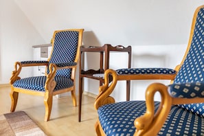 Een kamer met twee houten stoelen met blauw gestreept zitting en een houten tafel.