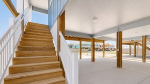 A wooden staircase leading to a covered outdoor area with a view of houses in the background. - PP189, Private Pool, Pet Friendly, Beautiful Sunsets (Port Aransas)