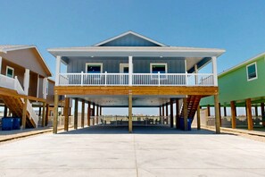 Une maison de deux étages située en bord de mer, dotée d’un balcon, d’une terrasse en bois et offrant une vue sur l’océan.