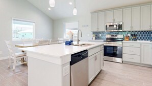 A modern kitchen with white cabinetry, stainless steel appliances, and a central island with a dishwasher. - PP189, Private Pool, Pet Friendly, Beautiful Sunsets (Port Aransas)