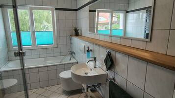 A modern bathroom with a bathtub, toilet, sink, and a large mirror.